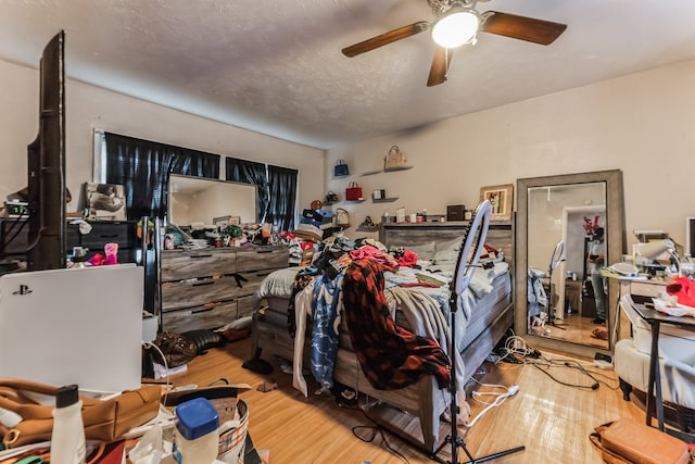 bedroom featuring light wood-type flooring, ceiling fan, and a textured ceiling