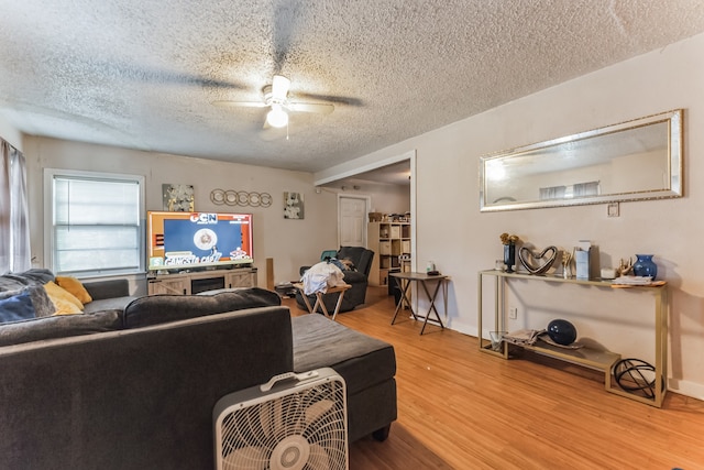 living room featuring light hardwood / wood-style floors, a textured ceiling, and ceiling fan