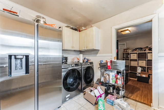 clothes washing area featuring cabinets, light tile patterned flooring, and washer and clothes dryer