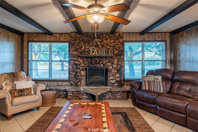 living room featuring beamed ceiling, light tile patterned flooring, ceiling fan, and wood walls