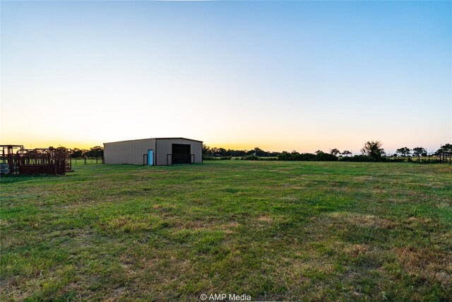 yard at dusk featuring an outdoor structure