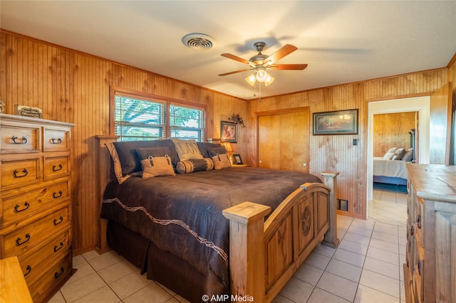 bedroom with light tile patterned floors, wooden walls, visible vents, a ceiling fan, and crown molding