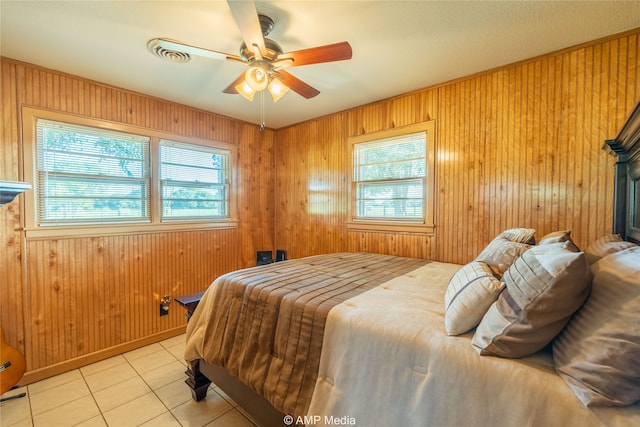 bedroom featuring wood walls, ceiling fan, and light tile patterned floors