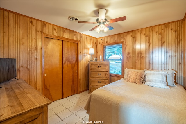 tiled bedroom featuring wood walls, a closet, and ceiling fan