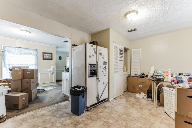 kitchen with white refrigerator with ice dispenser, a textured ceiling, and light tile patterned floors