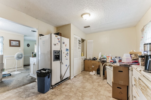 kitchen featuring a textured ceiling, light tile patterned floors, and white fridge with ice dispenser