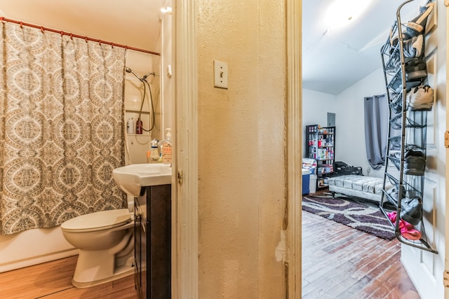 bathroom with lofted ceiling, wood-type flooring, and toilet