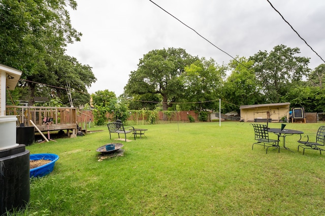 view of yard with an outbuilding, a deck, and a fire pit