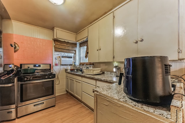 kitchen featuring light hardwood / wood-style floors, sink, light stone countertops, and stainless steel range with gas cooktop