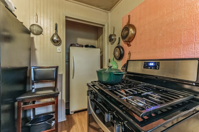 kitchen with appliances with stainless steel finishes, light hardwood / wood-style flooring, and decorative backsplash