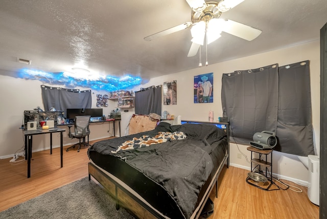 bedroom with ceiling fan, hardwood / wood-style floors, and a textured ceiling