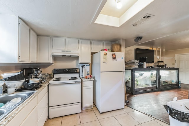 kitchen with white appliances, light tile patterned floors, sink, and white cabinets