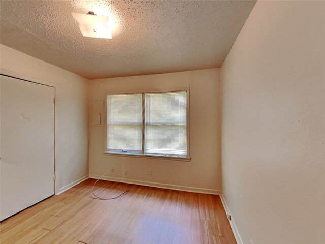 spare room featuring light hardwood / wood-style flooring and a textured ceiling