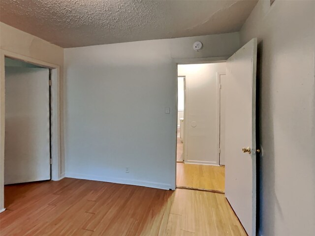 unfurnished room featuring light hardwood / wood-style flooring and a textured ceiling