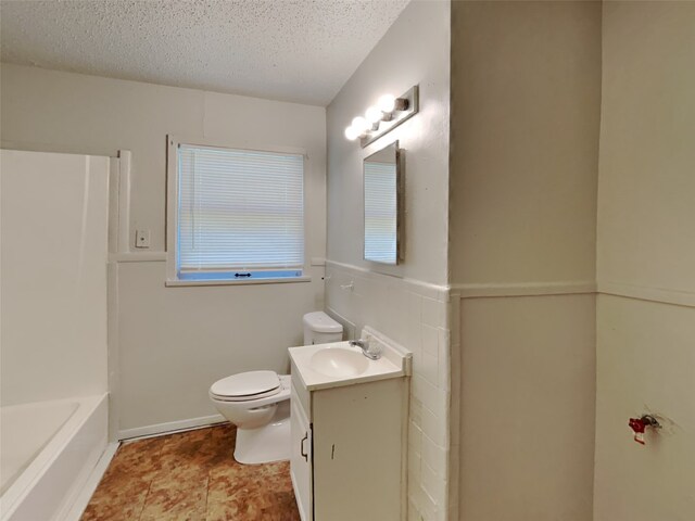 bathroom with tile patterned flooring, toilet, vanity, and a textured ceiling