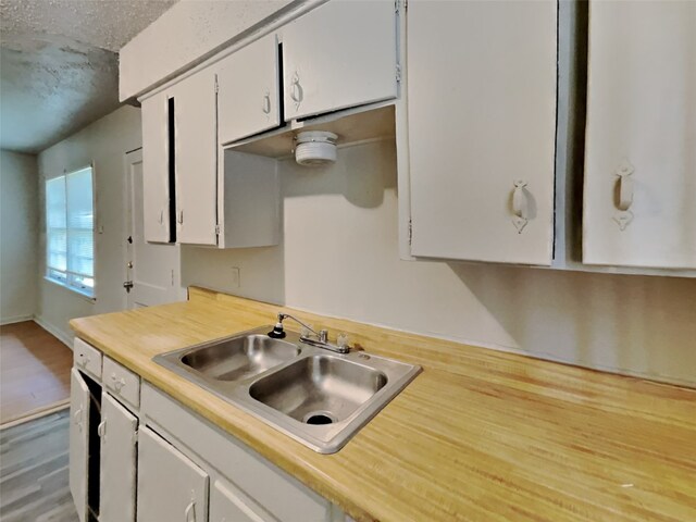 kitchen with white cabinets, hardwood / wood-style floors, sink, and a textured ceiling