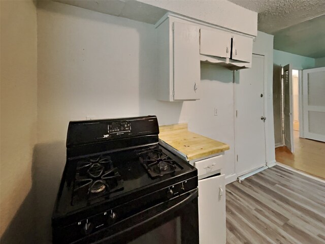 kitchen with range, white cabinetry, a textured ceiling, and light hardwood / wood-style flooring