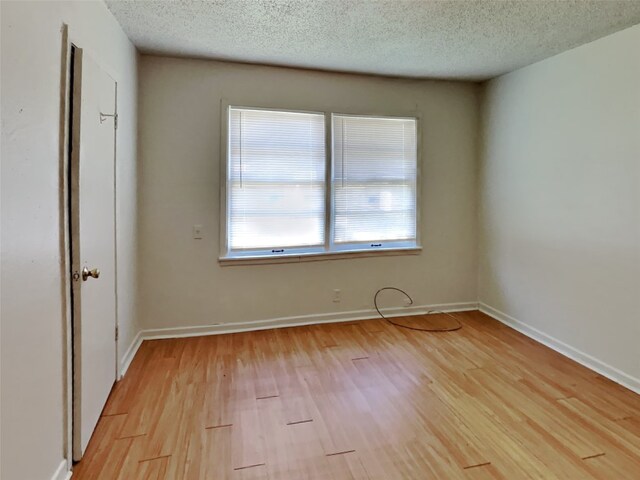 empty room with light hardwood / wood-style flooring and a textured ceiling