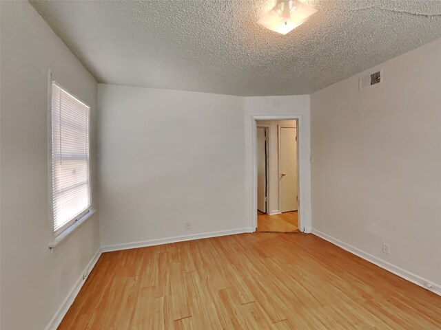 spare room with a textured ceiling and wood-type flooring