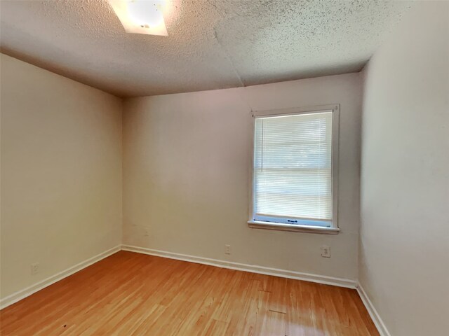 empty room with hardwood / wood-style floors and a textured ceiling