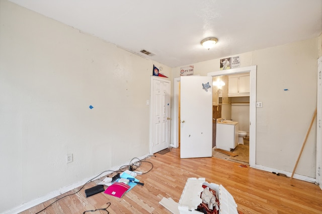 unfurnished bedroom with light wood-type flooring and connected bathroom