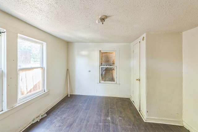 unfurnished room with dark wood-type flooring and a textured ceiling