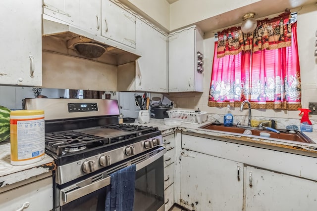 kitchen featuring under cabinet range hood, a sink, white cabinetry, light countertops, and stainless steel range with gas cooktop