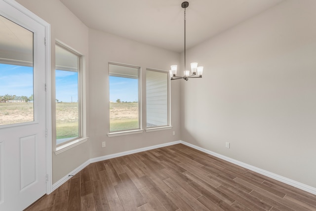 unfurnished dining area featuring a chandelier and hardwood / wood-style flooring