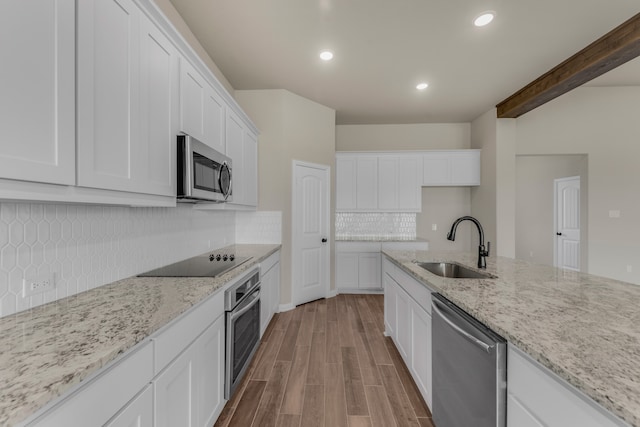 kitchen with appliances with stainless steel finishes, white cabinets, light stone countertops, light wood-type flooring, and sink