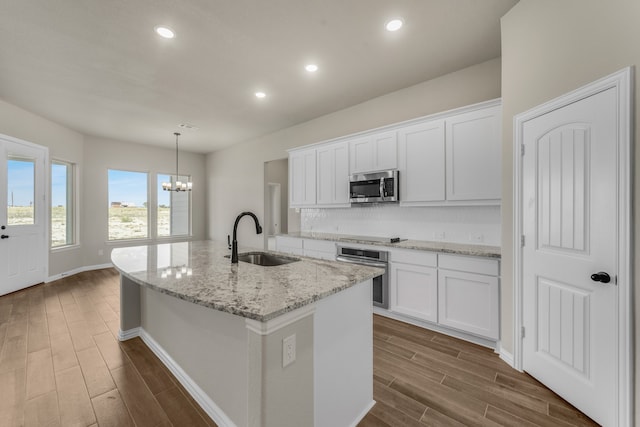 kitchen with white cabinetry, appliances with stainless steel finishes, a kitchen island with sink, and sink