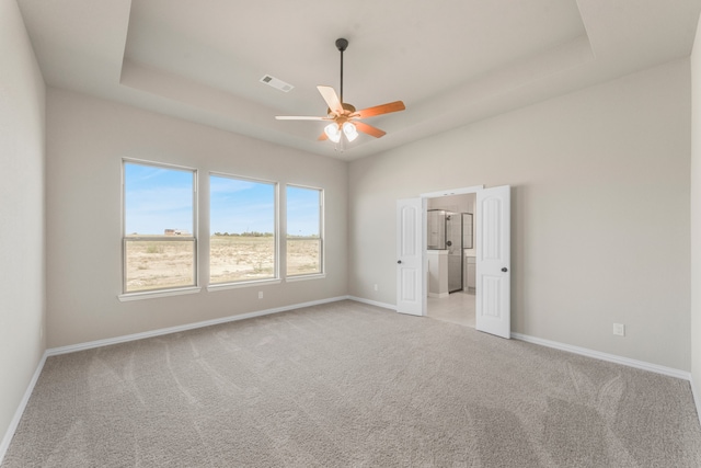 interior space featuring light carpet, a tray ceiling, and ceiling fan