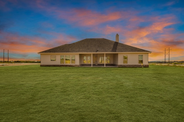 back house at dusk with a lawn and a patio area