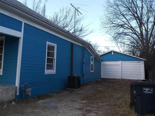 view of property exterior featuring cooling unit, a garage, and an outbuilding