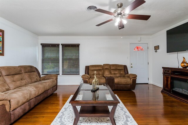 living room with dark hardwood / wood-style flooring, ceiling fan, and crown molding