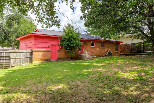 rear view of property with central AC and a lawn