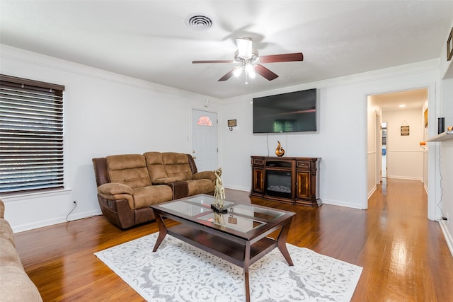 living room featuring hardwood / wood-style flooring, ornamental molding, and ceiling fan