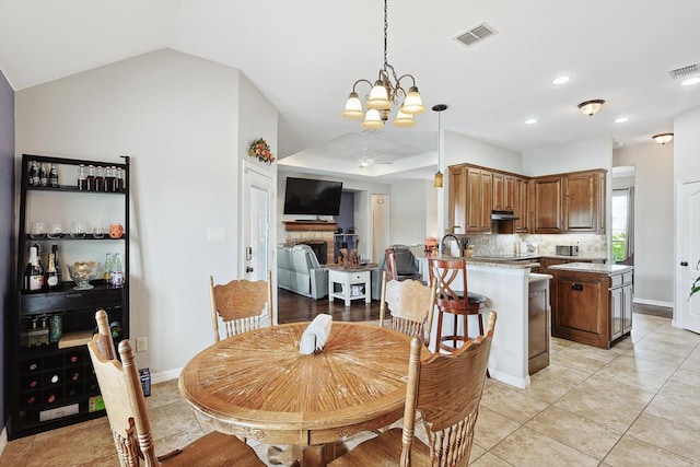 tiled dining room featuring an inviting chandelier and vaulted ceiling