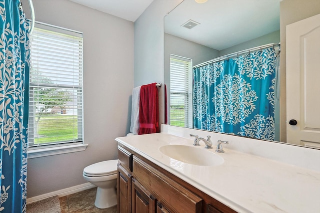 bathroom featuring vanity, tile patterned flooring, a wealth of natural light, and toilet