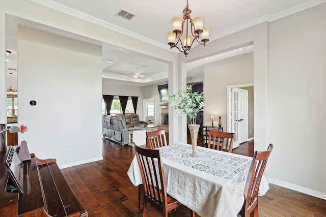 dining space featuring a tray ceiling, crown molding, ceiling fan with notable chandelier, and dark hardwood / wood-style floors