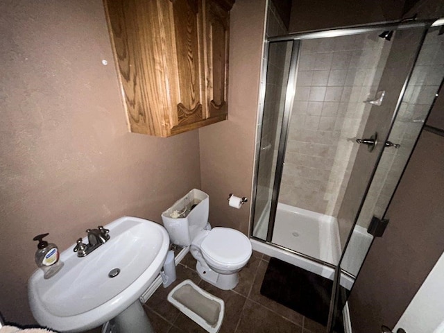 bathroom featuring tile patterned flooring, sink, a shower with door, and toilet