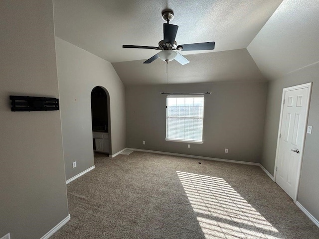 interior space featuring ceiling fan, vaulted ceiling, carpet, and a textured ceiling