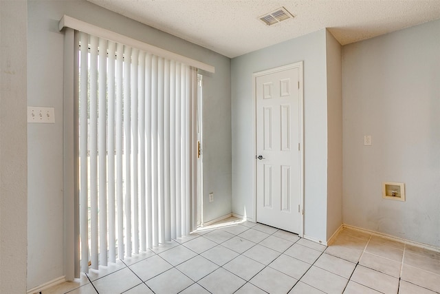 empty room with a textured ceiling and light tile patterned floors