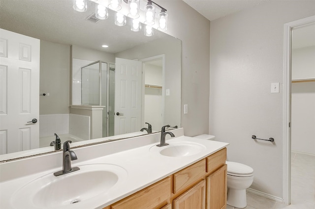 bathroom with toilet, double vanity, tile patterned flooring, and a textured ceiling