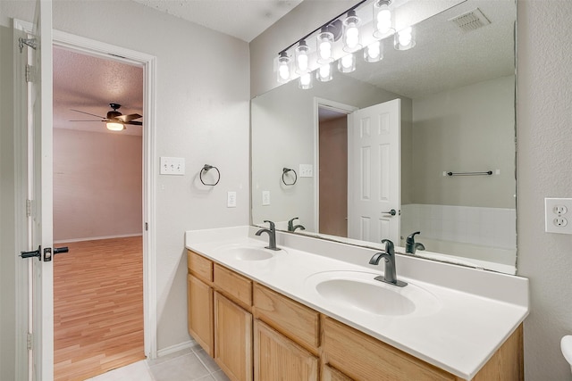 bathroom featuring tile patterned flooring, a textured ceiling, double sink vanity, ceiling fan, and a bathtub