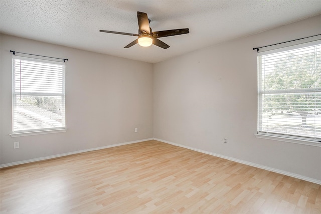 empty room with ceiling fan, plenty of natural light, and light hardwood / wood-style floors