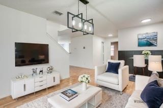 living room with light hardwood / wood-style floors and an inviting chandelier