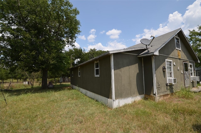 view of side of home featuring cooling unit and a lawn