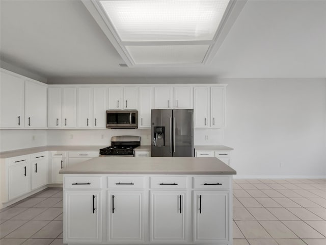 kitchen with stainless steel appliances, a center island, light tile patterned floors, and white cabinets