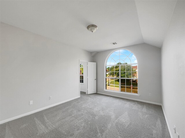 carpeted empty room featuring vaulted ceiling