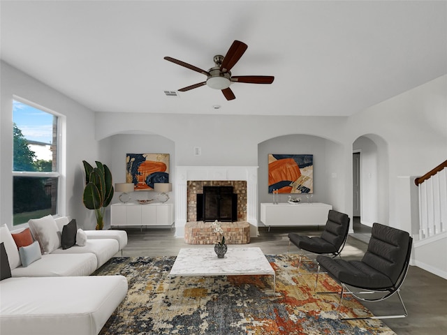 living room with ceiling fan, dark hardwood / wood-style floors, and a brick fireplace